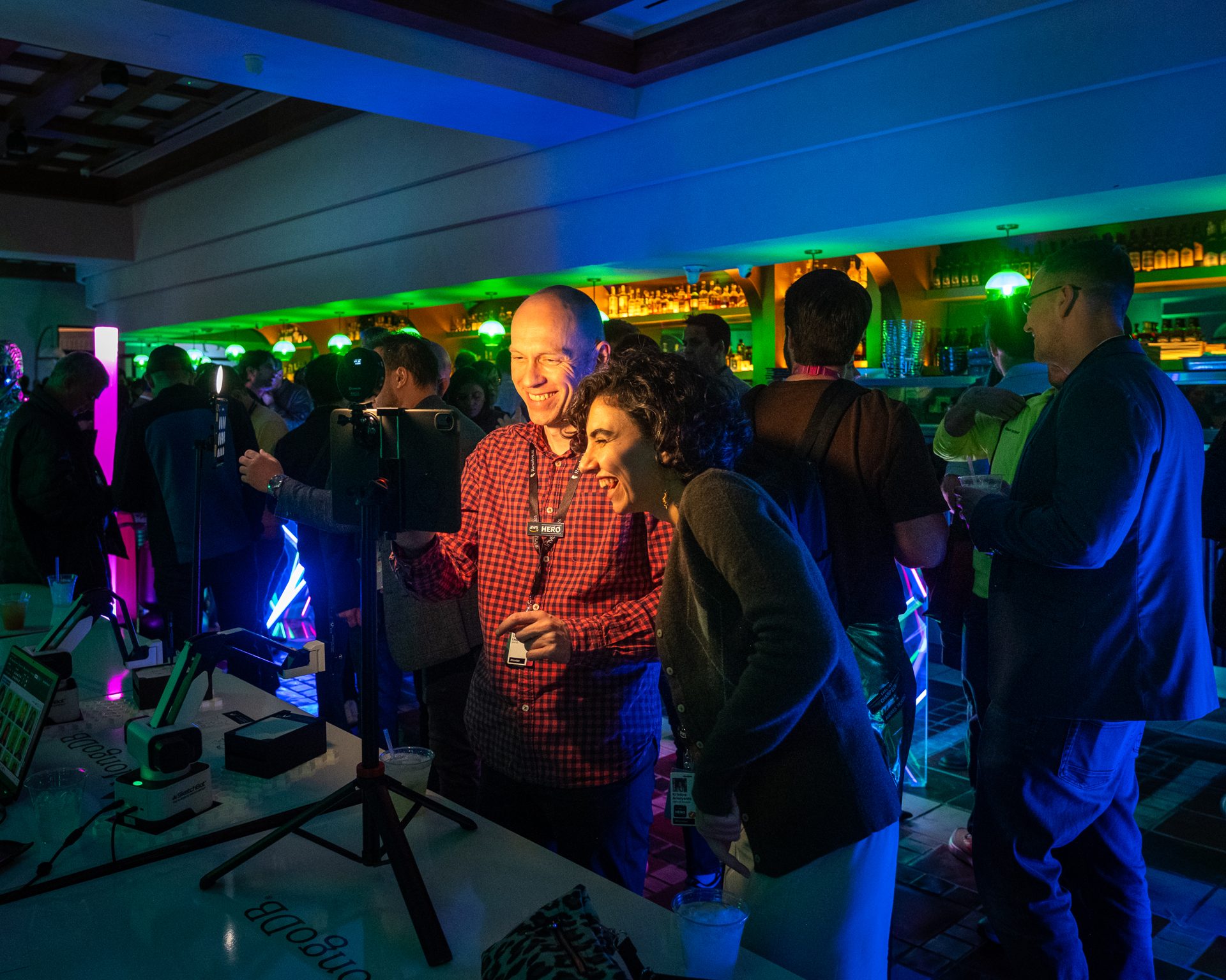 Guests laughing at the MongoDB interactive demo bar during the AWS conference reception at Sugarcane Las Vegas